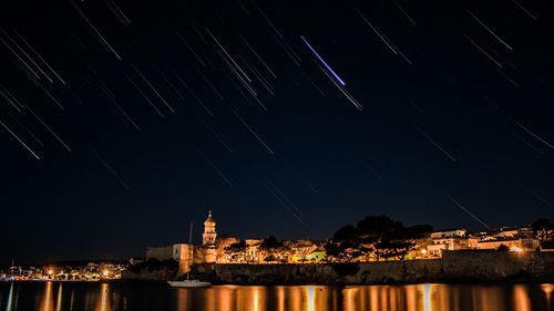 Illuminated buildings against sky at night