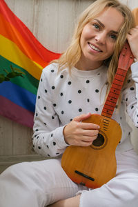 Young millennial hippie woman sitting on balcony play guitar. music lesson and singer sitting. lgbtq 