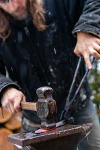 Midsection of blacksmith working in workshop