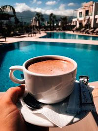 Close-up of hand holding coffee cup in swimming pool