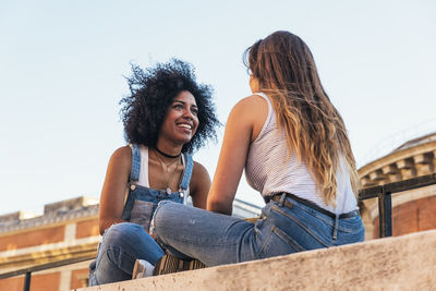 Portrait of smiling young woman sitting against built structure