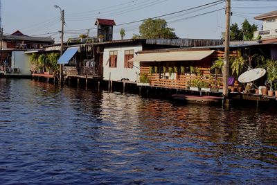 Houses by river and buildings against sky