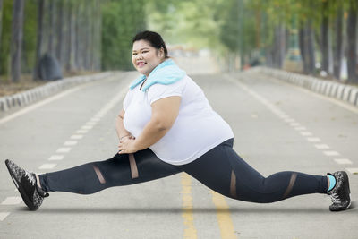 Portrait of smiling young woman exercising on road