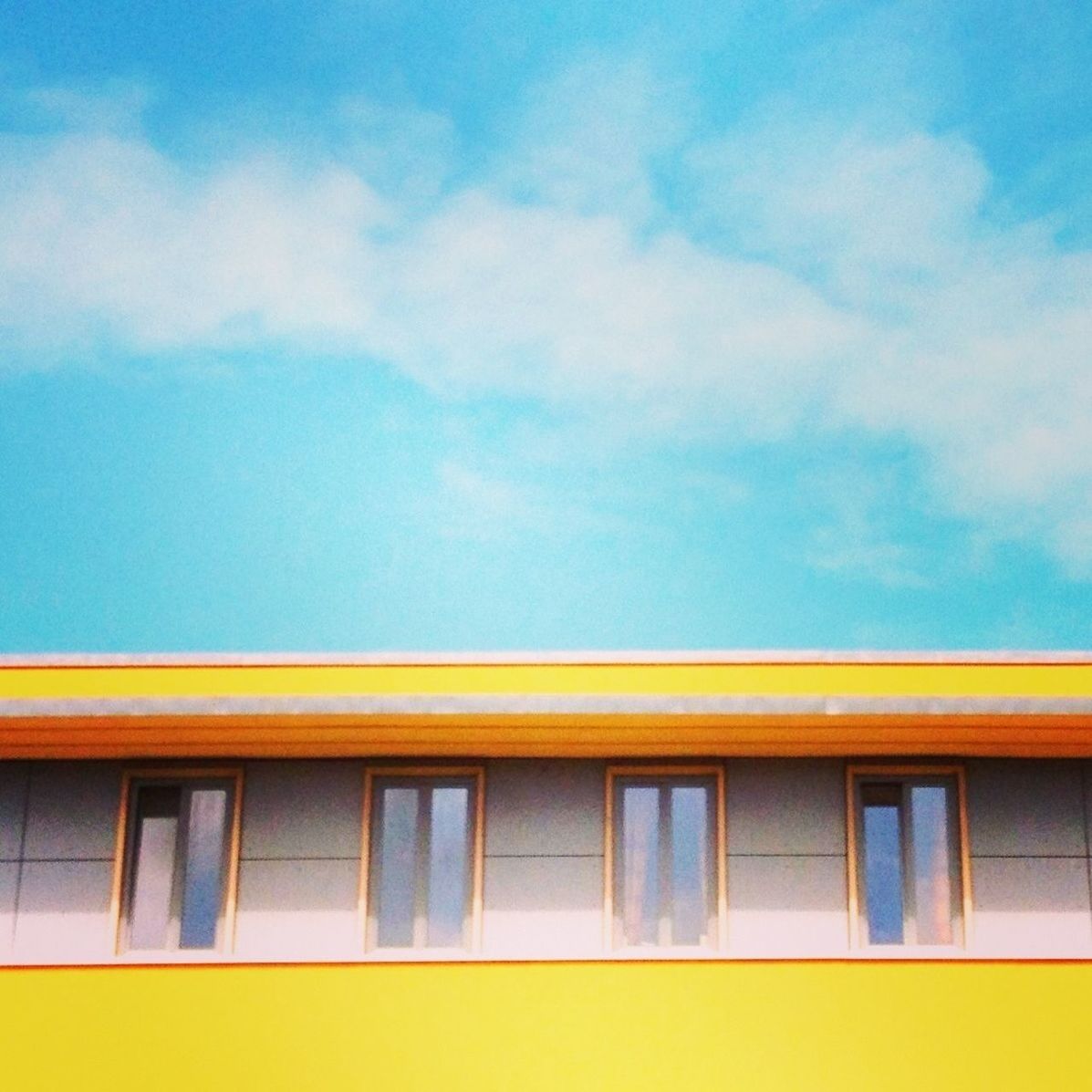 architecture, built structure, building exterior, low angle view, yellow, window, sky, building, residential building, residential structure, blue, high section, outdoors, no people, city, day, house, balcony, cloud, cloud - sky