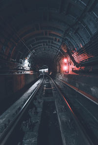 Railroad tracks in illuminated tunnel