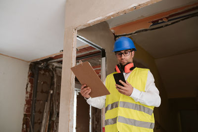 Foreman or architect working on mobile phone blueprints .construction site. home improvement