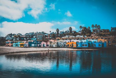 Houses by river against sky in town