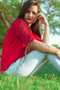 Beautiful young woman sitting on field