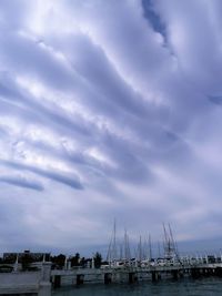 Sailboats in sea against cloudy sky