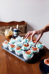 Decorating homemade chocolate muffins with blue cream topping and fig