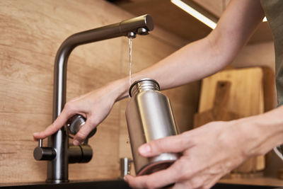 Woman pouring water in metal eco friendly bottle. zero waste concept