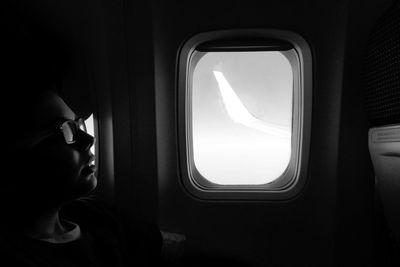 Boy sitting by window while traveling in airplane