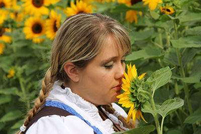 Close-up of woman with braided hair smelling sunflower