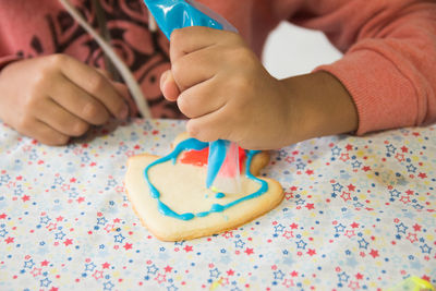 Close-up of hands decorating cookies