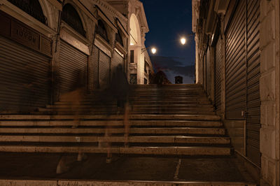 Low angle view of illuminated street amidst buildings at night