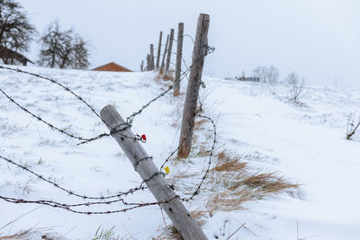 Barbed wire fence with fallen pillars in winter snowy bavarian mountain landscape.