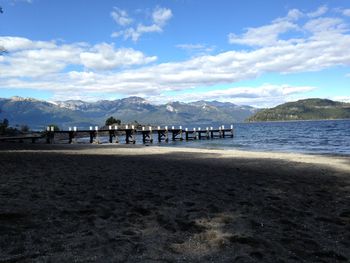 Scenic view of mountains and beach against cloudy sky