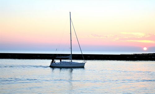Sailboat sailing on sea against sky during sunset