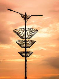 Low angle view of electricity pylon against orange sky