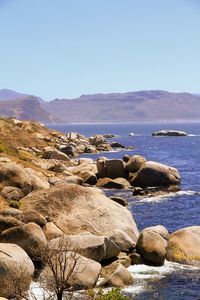 Rocks by sea against clear sky