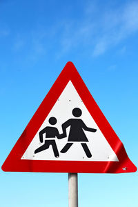 Low angle view of road sign against blue sky