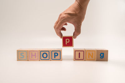 Close-up of hand holding toy blocks against white background