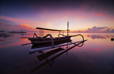 Boat moored on sea against sky during sunset