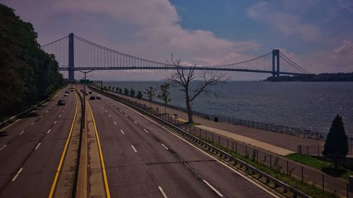 View of suspension bridge over river against cloudy sky