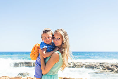 Happy woman standing at beach against sky