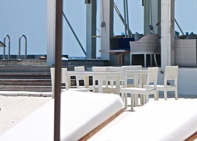 Empty chairs and table arranged at poolside