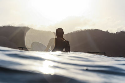 Female surfer in the ocean at sunset