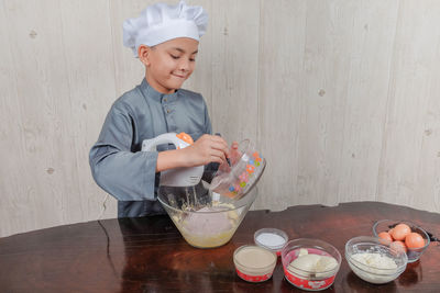 Boy mixing flour and egg yolk in bowl