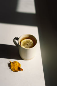 Flat lay of pumpkins, dried leaves, accessories and tea with lemon in cup on wooden background.