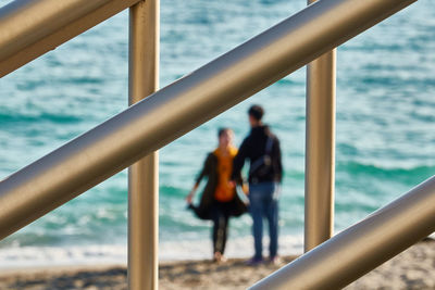 People standing by railing against sea