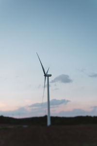 Silhouette wind turbines on field against sky during sunset