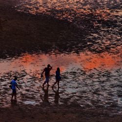 Reflection of people in water at sunset