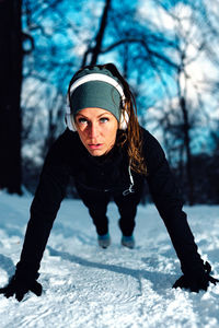 Woman doing push-ups on snow covered field