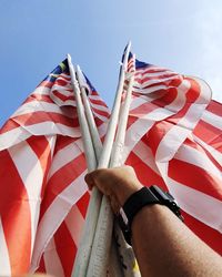 Low section of person holding flag against sky