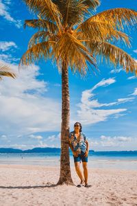 Full length of palm tree on beach against sky