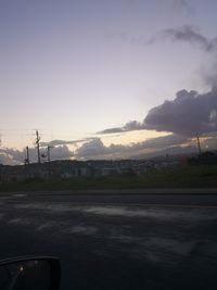 Road by city against sky during sunset