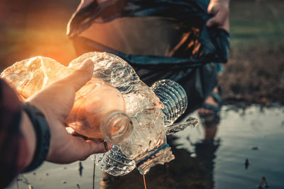 Cropped hand of person disposing plastic bottles