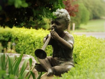 Statue of boy playing musical instrument