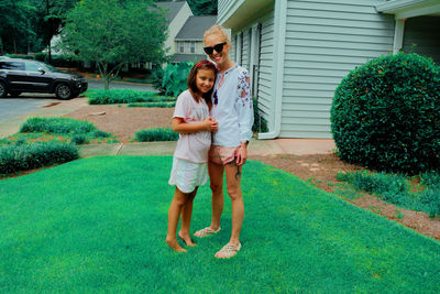 Full length of woman and girl standing at lawn