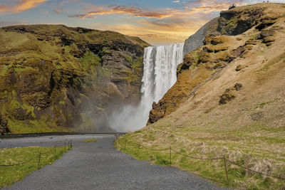 Scenic view of beautiful skogafoss against cloudy sky during sunset