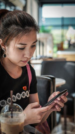 Close-up of young woman using mobile phone while sitting at cafe