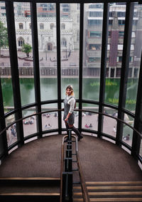 Full length of man standing by railing against window