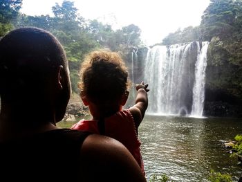 Rear view of friends holding water against sky