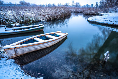 Boats moored in lake during winter