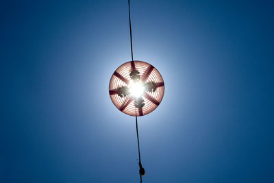 Low angle view of illuminated lighting equipment against blue sky