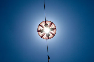 Directly below shot of lighting equipment on rope against clear blue sky